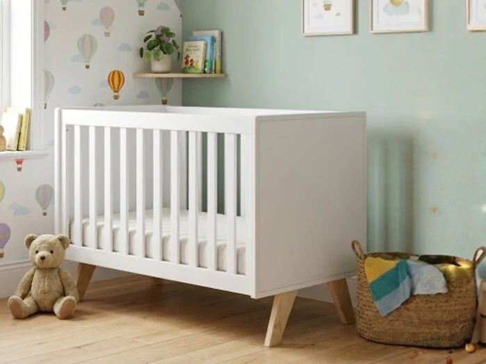 Mathy By Bols Madavin adjustable cot bed with natural birch legs in nursery